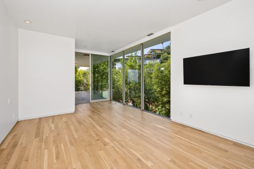 A spacious living room with a large flat-screen TV mounted on a white wall. California, USA