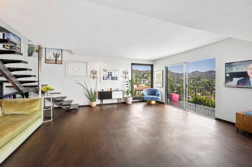 A spacious room with white walls and wood floors beneath stairs. California, USA