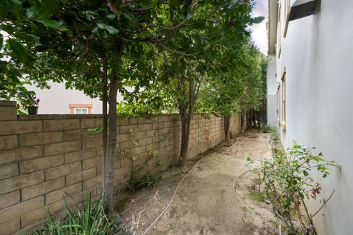 A stone wall by the house lined with green trees. California, USA