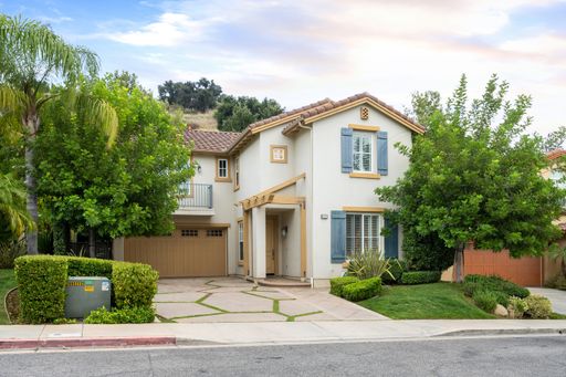 A two-story house with a garage and front yard trees. California, USA