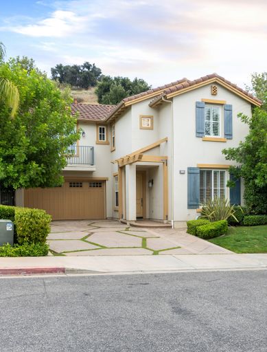 A two-story house with a garage and front yard trees. California, USA