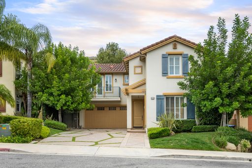 A two-story house with a garage and front yard trees. California, USA