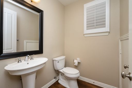 A bathroom featuring a toilet, sink, and adjacent mirror