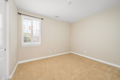 An empty room with tan walls and a window with blinds. California, USA