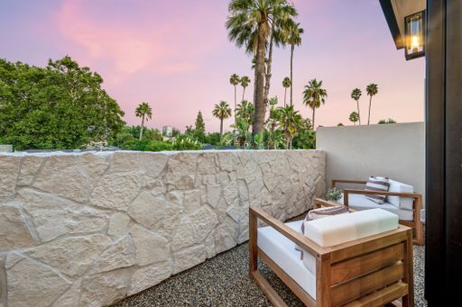 The two armchairs on a balcony overlooking lush green palm trees. California, USA