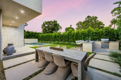 An outdoor table and chairs on a patio with green vegetation in the background. California, USA