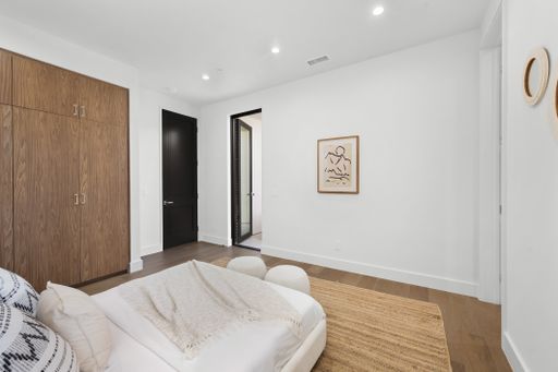 A modern living room with white walls, wooden floor, and wall art