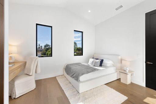 A modern bedroom with a bed and desk positioned by a window