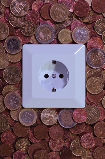 A close-up of an electrical outlet set against a background of various euro coins.