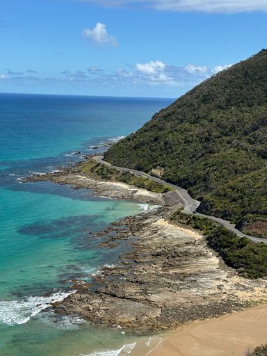 A Scenic coastal view with a winding road along the shoreline and clear blue waters under a bright sky