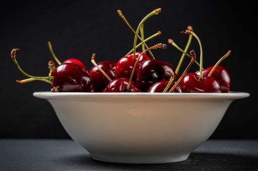 A closeup shot of fresh cherries in a bowl on a black surface