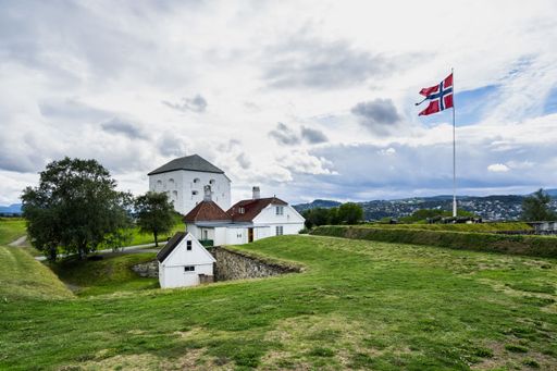 The Kristiansten Fortress surrounded by hills covered in greenery under a cloudy sky in Norway