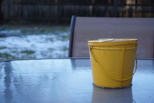 A selective focus shot of a yellow wet bucket on a reflecting table