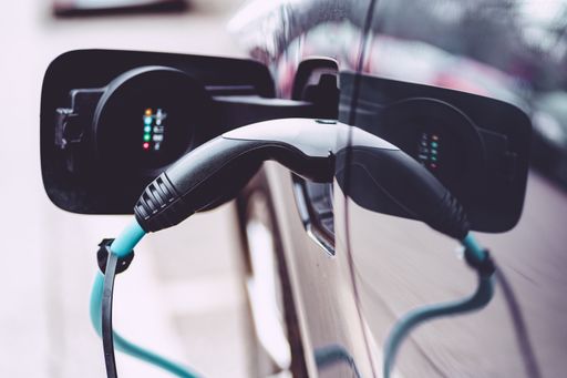 Close-up of a modern electric car which was parked at a charging station for recharging. The charging cable is plugged into the car
