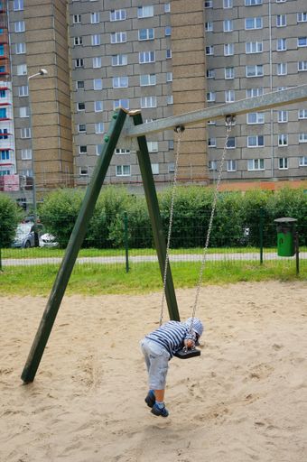 A Young boy hanging on a swing at a playground