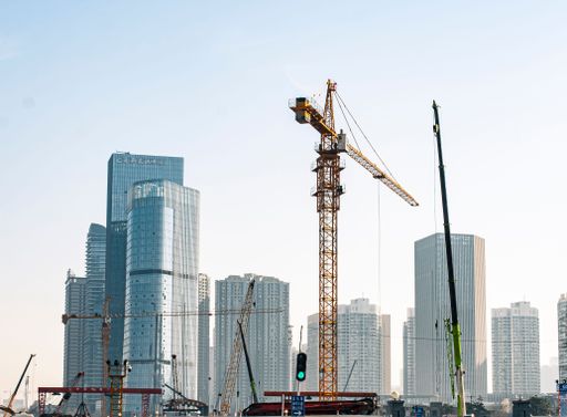 A huge construction site on a sunny day in Wuhan city, with a backdrop of skyscrapers under the blue sky, China