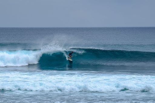A Surfer riding a wave on a sunny day in Uluwatu, Bali, Indonesia