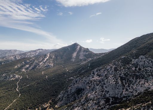 A scenic view of a mountain range with winding paths under a clear blue sky