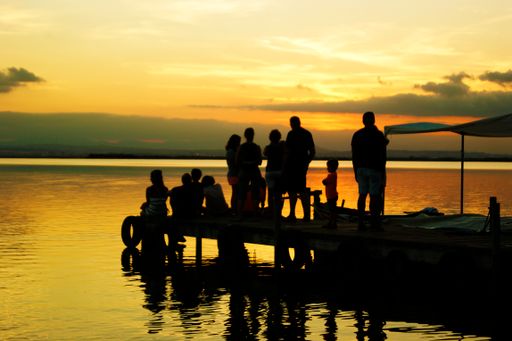 The silhouettes of tourists on a pier on the sea during a beautiful golden sunset