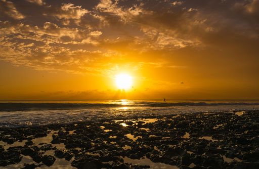 A scenic view of golden sunset over a rocky shoreline