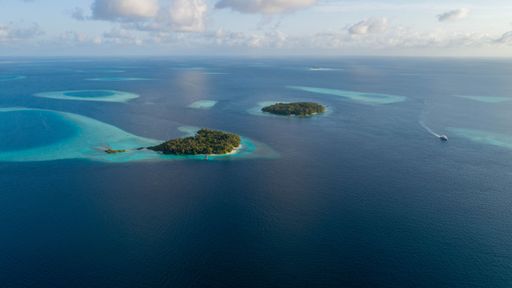 An aerial view of tropical islands surrounded by turquoise waters and coral reefs in the Maldives.