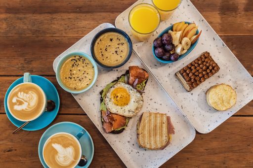 A high angle shot of a breakfast table with coffee, egg toast and fruits