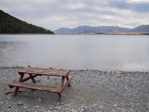 A closeup of a wooden picnic table with attached benches on the peaceful lakeshore