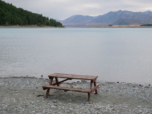 A wooden picnic table on the shore of a scenic lake