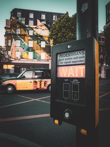 A closeup shot of a wait signal in Kings Cross, London, UK with cars and buildings in the background