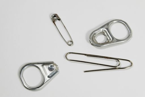 Still life articles of metal daily use paper clip, can opener and clip needle.