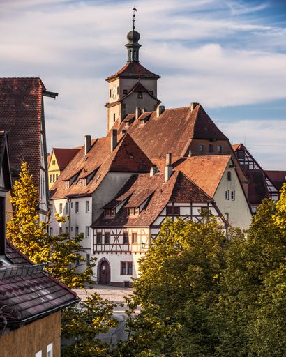 The view of a historic building with a clock tower against blue sky in Rothenburg ob der Tauber, Bavaria, Franconia, Germany
