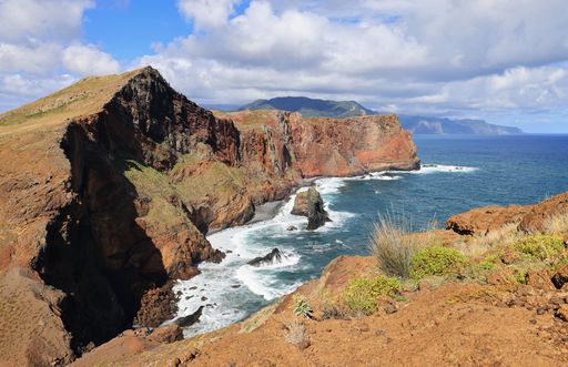 The majestic cliffs surrounded by blue waters under cloudy sky in Vereda da Ponta de Sao Lourenco, Madeira, Portugal