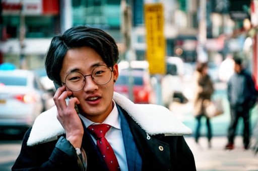 A young Korean fashionista man talking on the phone in the streets of Mokpo City in South Korea