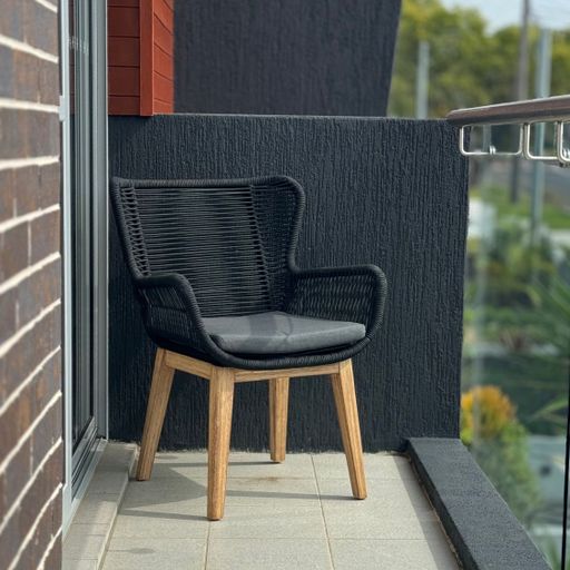 A modern black chair with wooden legs on a small balcony with a view