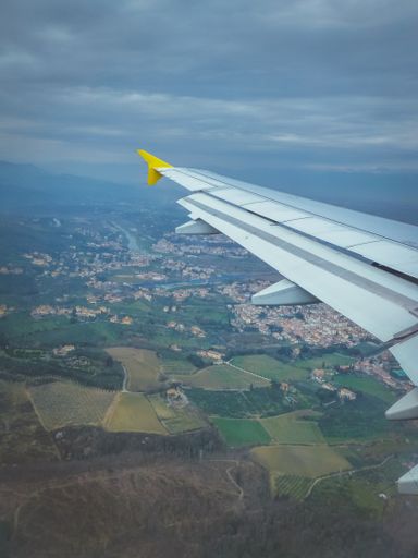 A vertical shot from a plane of buildings under a cloudy sky