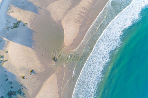 Aerial view of a sandy beach with clear water and gentle waves