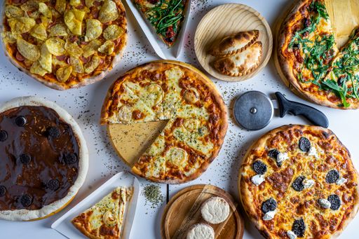 A close-up shot of different  pizzas on a table in a pizzeria