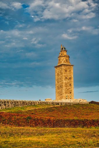 A vertical shot of Tower of Hercules in A Coruna, Galicia, Spain with a cloudy blue sky in the background