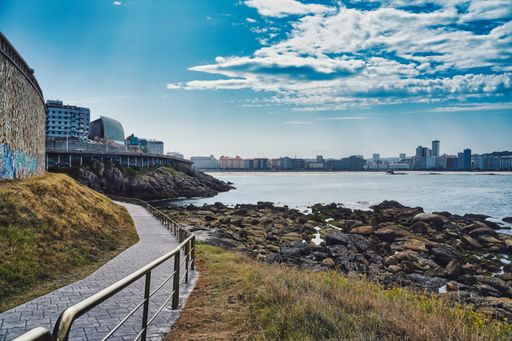 A narrow pathway near the sea under a blue sky in Galicia, Spain