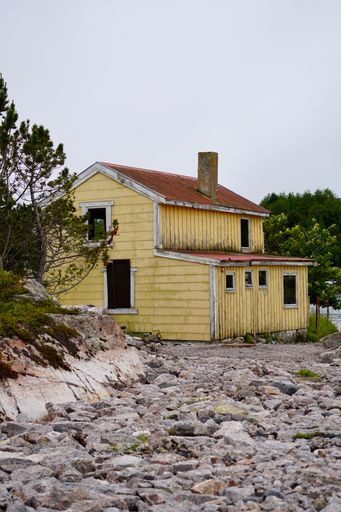 A vertical shot of an abandoned building on the island of Meloeya on a cloudy day in Kristiansund, Norway