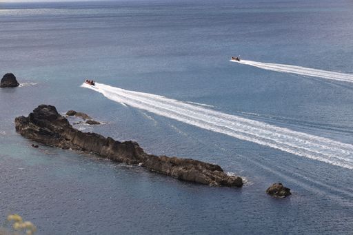 Aerial view of two speedboats leaving trails on the blue sea around rocky islands