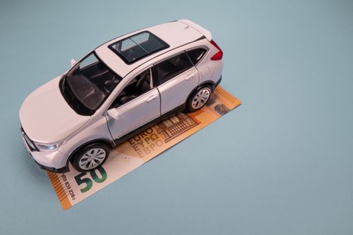 Miniature White car model on Euro banknote bill background with copy space. Business, finance or budget plan money saving for buying a new car.
