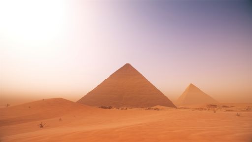 A scenic view of pyramids in the middle desert against a misty sky
