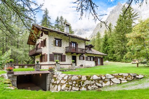A charming stone house surrounded by lush greenery and mountains in a serene forest setting