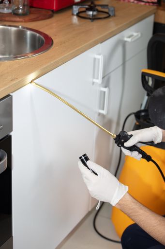 A vertical picture of a person disinfecting the kitchen under the lights - coronavirus concept