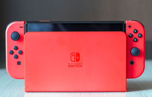 A close-up of a red Nintendo Switch console on a wooden surface
