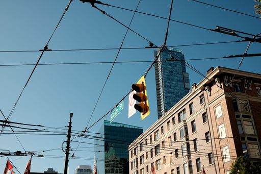 An urban scene of Robson Street in downtown Vancouver with traffic lights and overhead wires