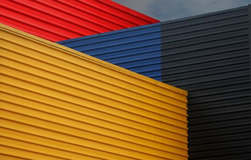 Colorful geometric abstract pattern with red, blue, yellow, and black corrugated metal panels.