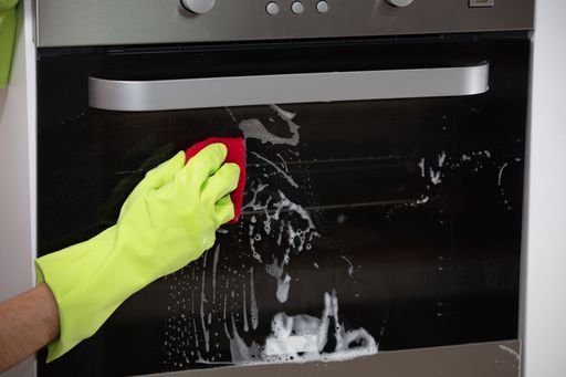 A closeup of a person with gloves disinfecting the oven under the lights - coronavirus concept