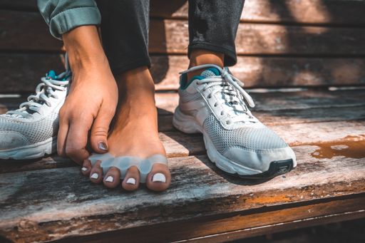 A closeup shot of a female wearing sneakers and toe separators outdoors